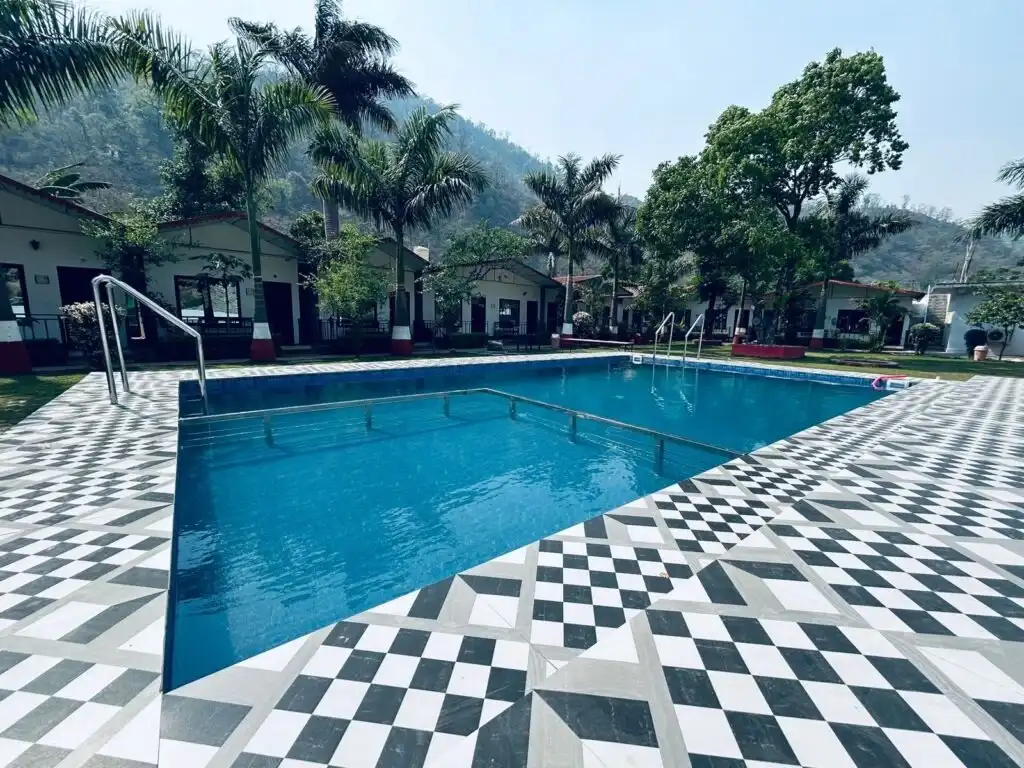Outdoor swimming pool with cottages and palm trees at RS08 resort