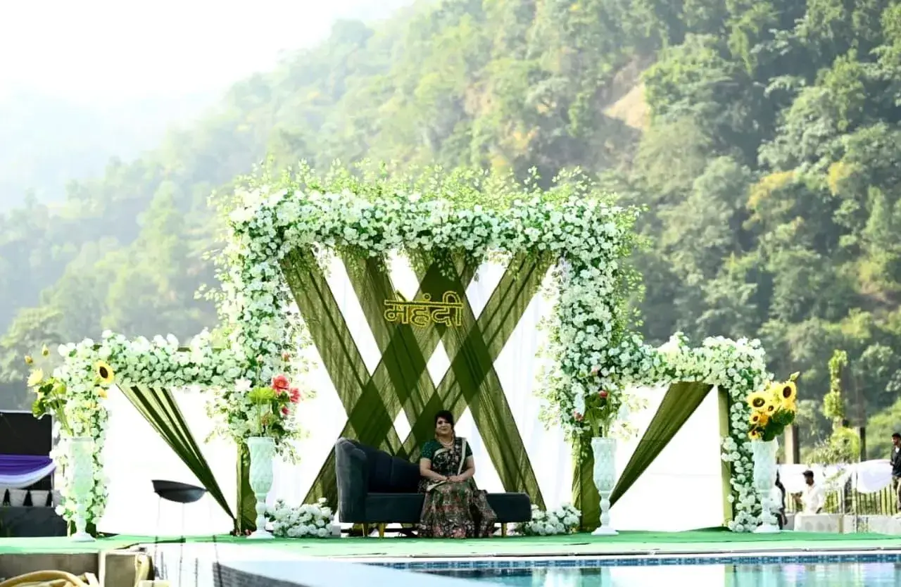 Luxury poolside wedding stage in Rishikesh with floral backdrop and scenic hill views for destination wedding
